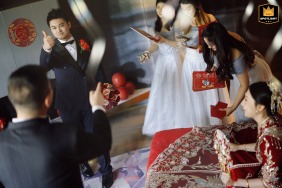 Groom and groomsmen play a game in a hotel room before a wedding. The photo shows a pre wedding activity with the men appearing focused.
